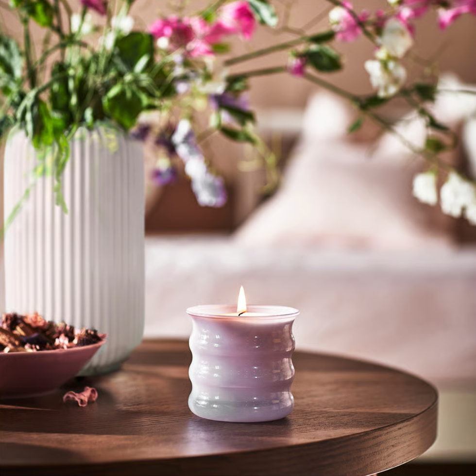 a candle and decorative bowl on a wooden table accompanied by a flower vase