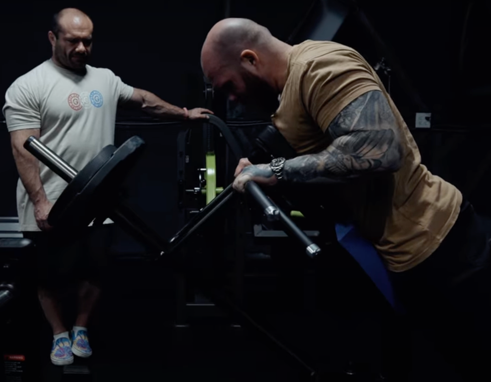 two individuals engaged in a gym workout one performing an exercise on a machine