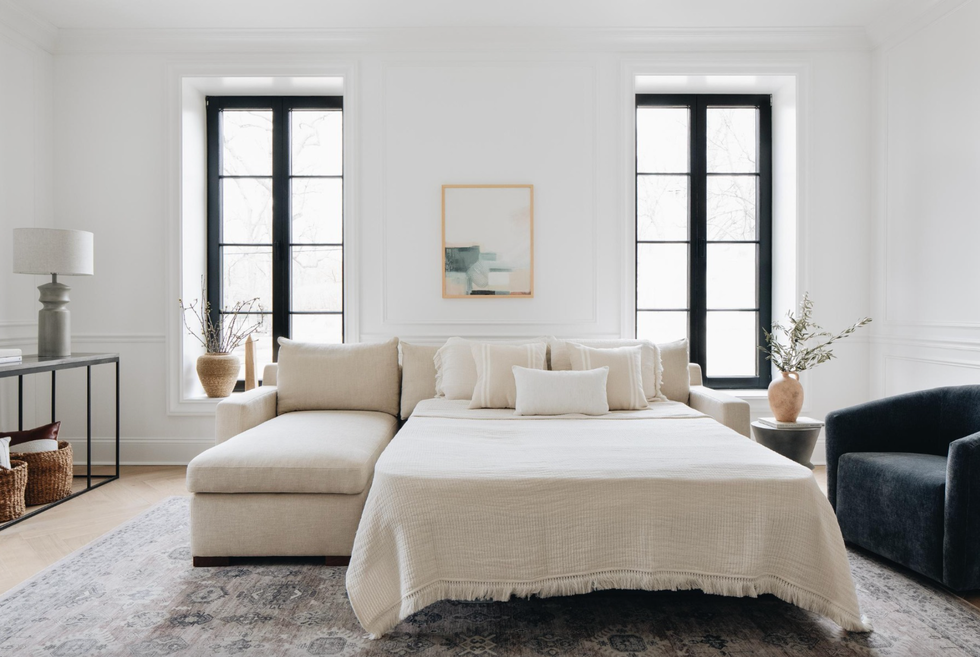 a cream sleeper sofa from interior define that's fully extended in a living room setup