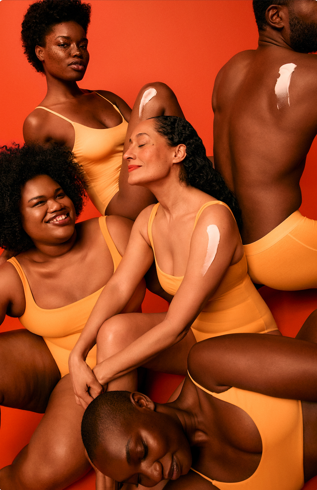 group of individuals wearing matching yellow swimsuits against an orange backdrop showcasing skin care products