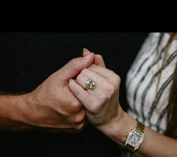 two hands holding each other with an engagement ring prominently displayed
