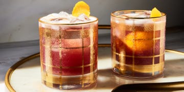 a red tinted sour garnished with an orange twist