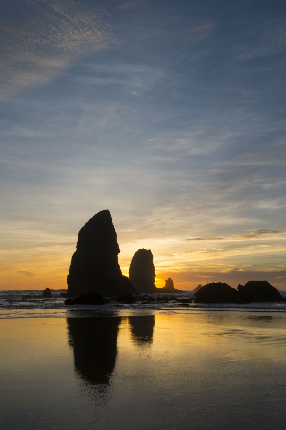 Sea stacks silhouetted at sunset during low tide at Cannon...