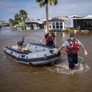 hurricane ian flooding neighborhoods and two rescue men with a boat walk through knee high waters