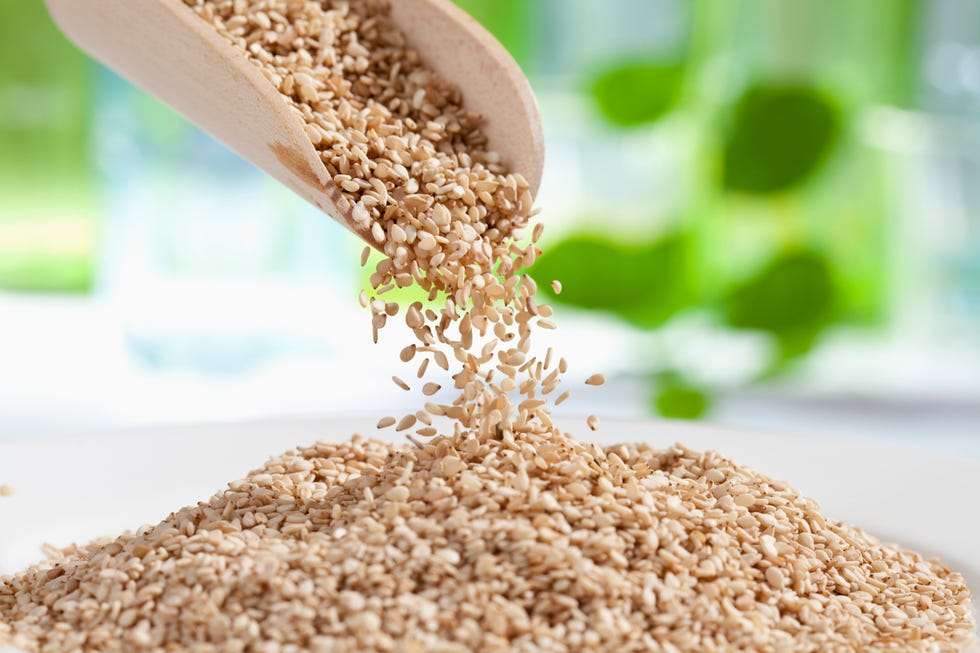 seasame seeds pouring from wooden scoop, close up