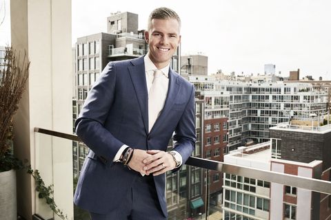 ryan serhant leans on a balcony railing overlooking the city