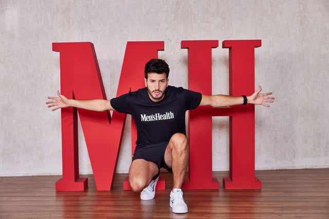 el cantante posa ante las letras m h con una camiseta negra