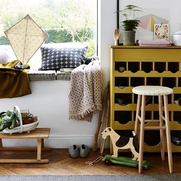 second hand furniture in a hallway used furniture a yellow dresser, window seat, wooden stool, woollen blanket and cushion and shoe rack