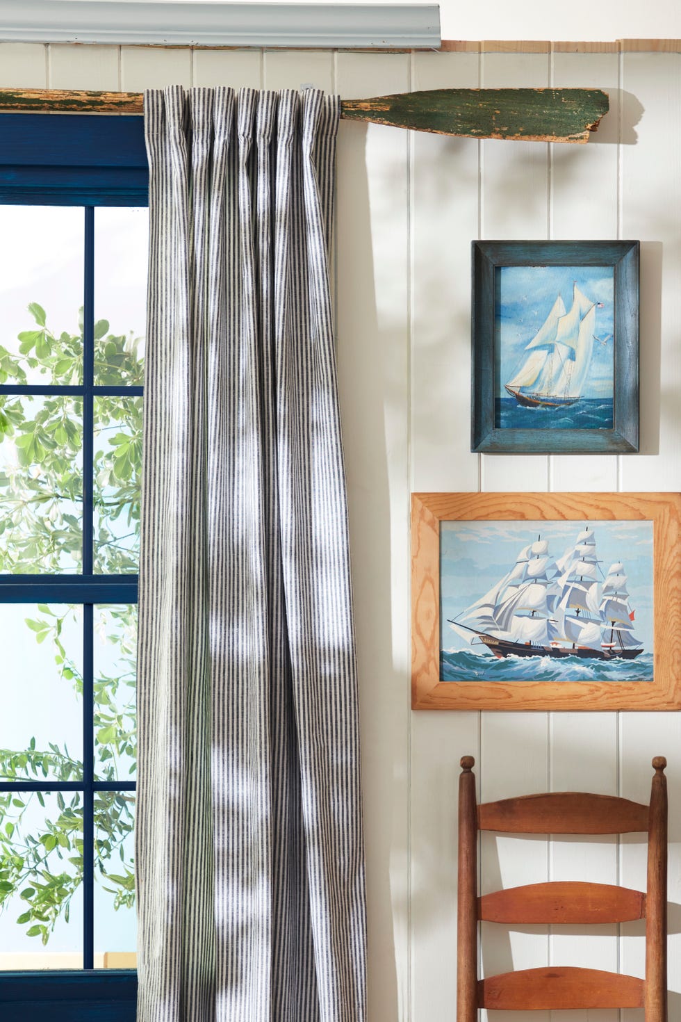 room with oar used as curtain rod and seascapes hanging
