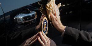 secret service agent cleans the presidential seal on a vehicle