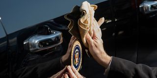 secret service agent cleans the presidential seal on a vehicle