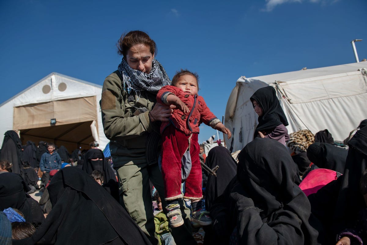 Sheikha Ibrahim 33 tilt een kind op tijdens haar crowdcontrolronde De Koerdische commandant van de veiligheidstroepen werkt in het door Koerden geleide vluchtelingenkamp alHol in NoordSyri Hier verblijven duizenden vrouwen vaak met hun kinderen Ze hebben zich eerder overgegeven of zijn gevlucht uit ISbastions