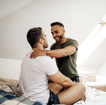 seductive gay couple at home in bedroom, enjoying tender kisses and hugs