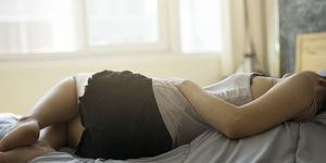 Vrouw ligt in bed met buikpijn