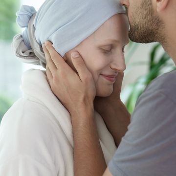een man kust zijn vrouw met kanker op haar voorhoofd