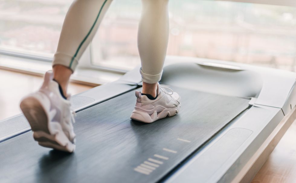 selectively blurred detail of legs running on a treadmill a warm light enters through the window in the background