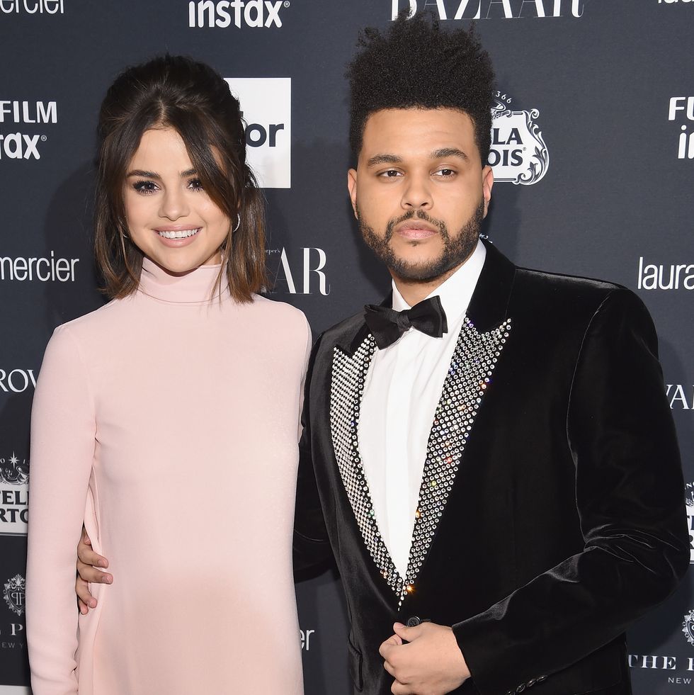 a woman in a pale pink turtleneck dress and a man in a black and white tuxedo embrace and pose for photos