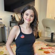 selena gomez smiling and wearing a black tank top with an "i voted" sticker