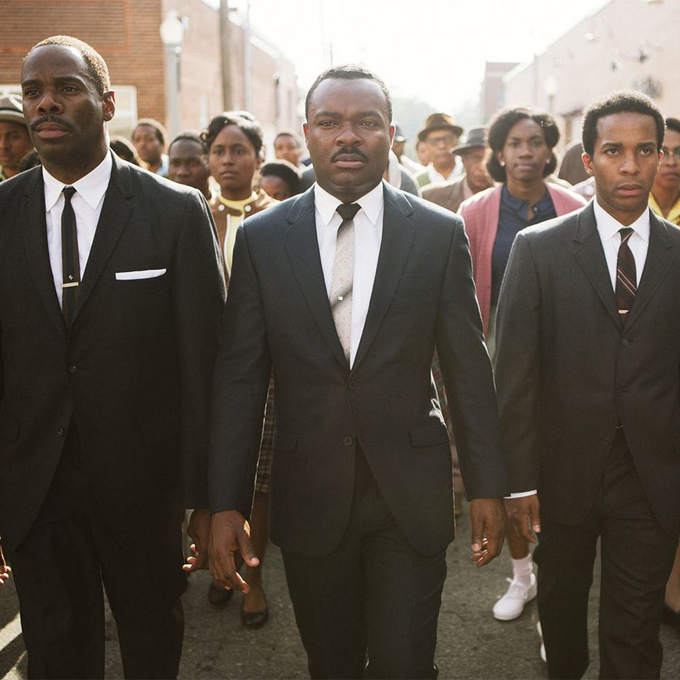 group of individuals walking in suits through a street