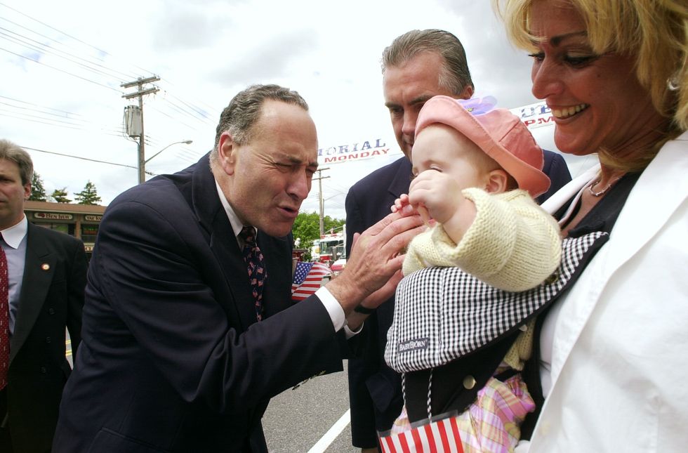 sen chuck schumer stops to greet a tot while marching in th