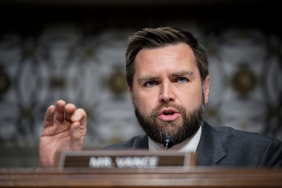 jd vance gesturing with his hand as he speaks behind a microphone at a podium