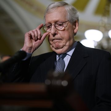 mitch mcconnell adjusts his glasses while standing at a podium
