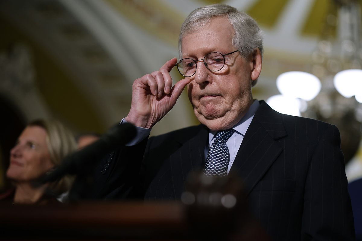mitch mcconnell adjusts his glasses while standing at a podium