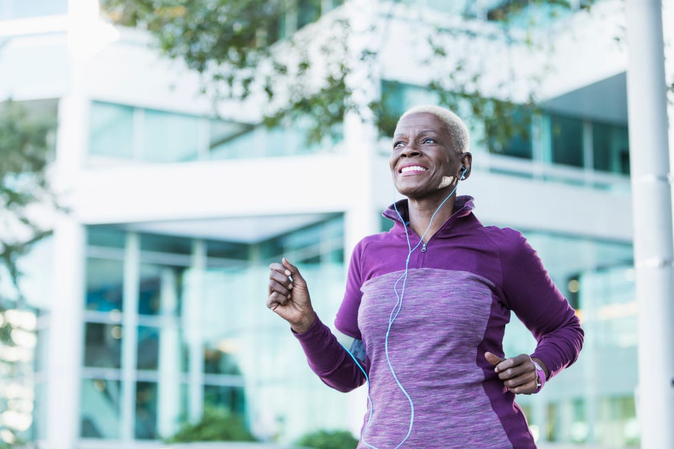 senior african american woman exercising outdoors with earphones in
