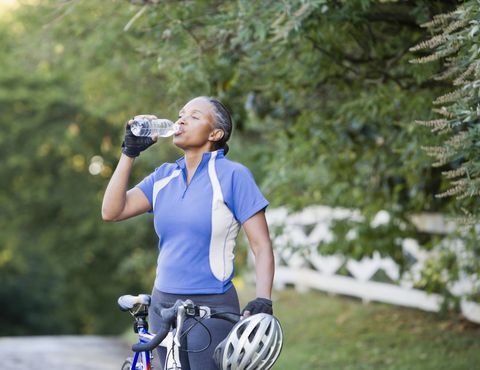 Senior African female cyclist drinking water