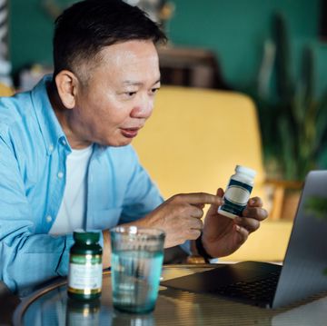 senior asian man having a virtual appointment with doctor online, consulting his prescription and choice of medication on laptop at home telemedicine, elderly and healthcare concept