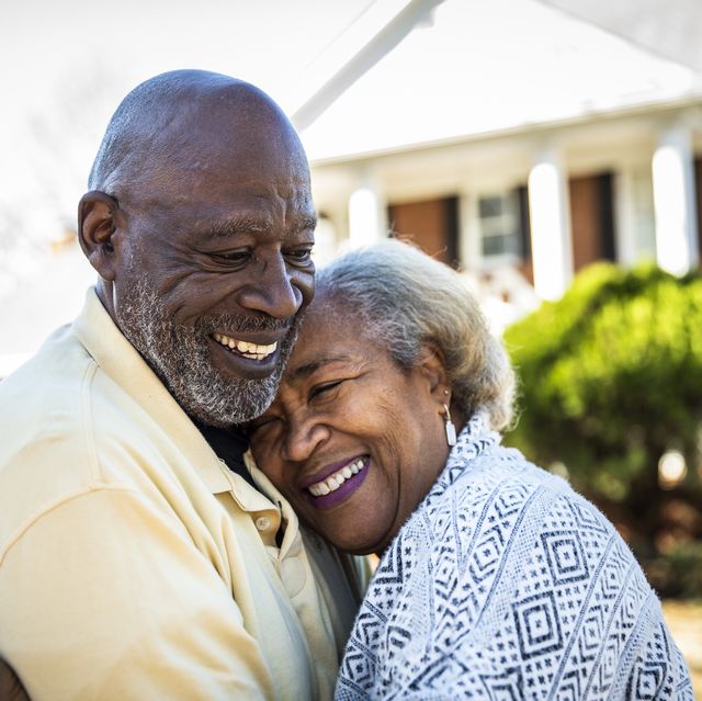senior couple embracing in front of residential home
