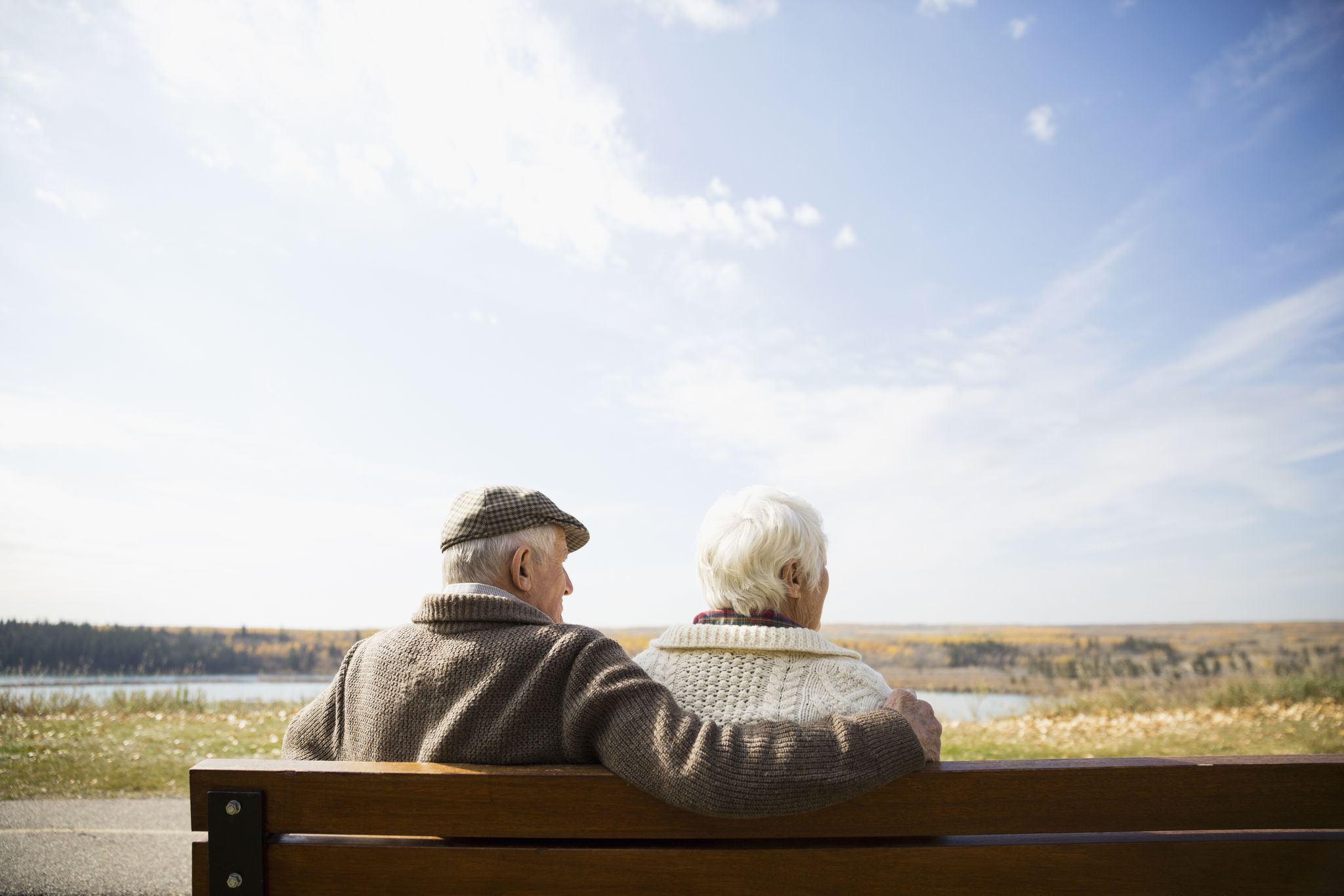 Senior couple sitting on bench looking at sunny autumn view