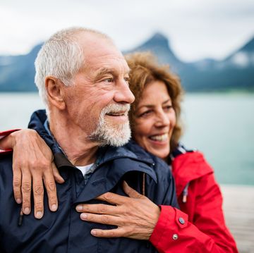 senior couple tourist standing by lake in nature on holiday, hugging