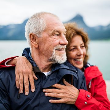 senior couple tourist standing by lake in nature on holiday, hugging