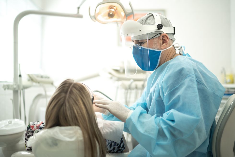 senior dentist examining the teeth of a young woman