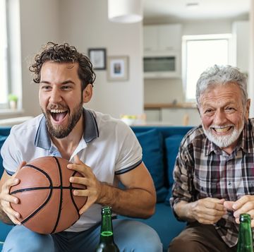 senior father and adult son basketball fans watching basketball game on tv