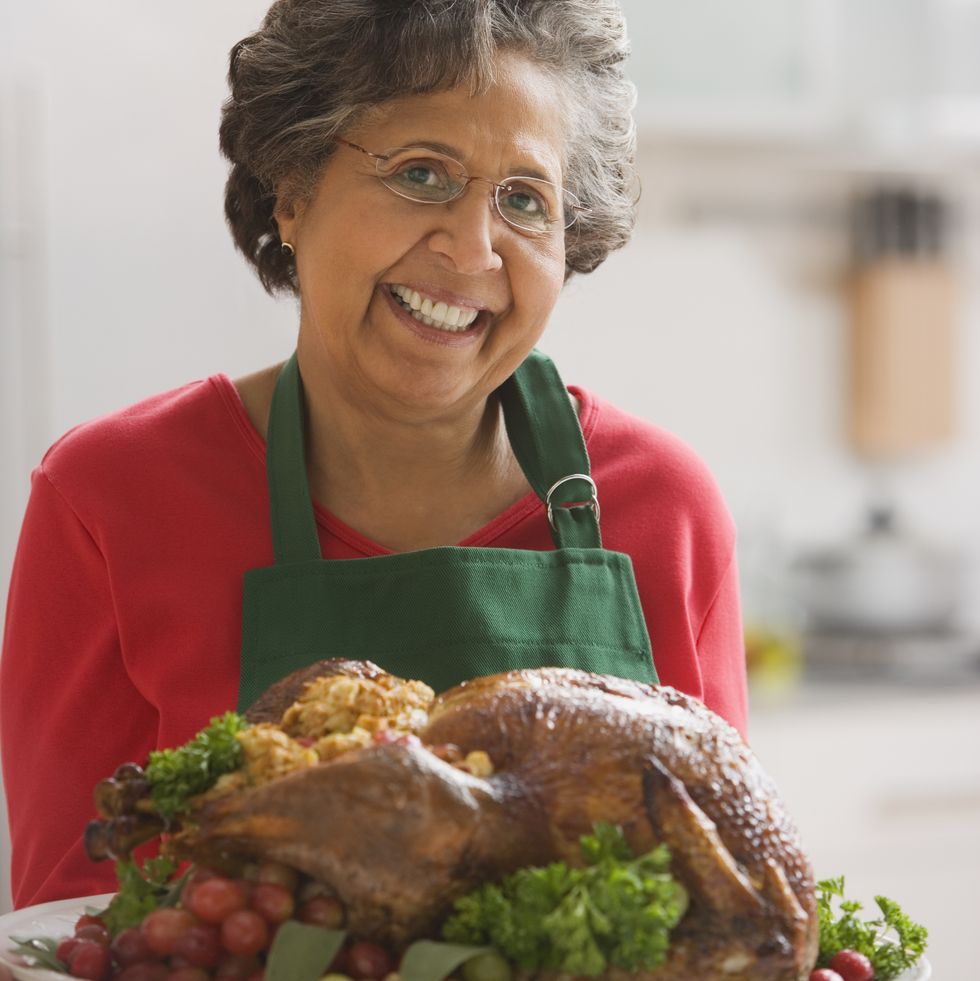 senior hispanic woman holding roasted turkey