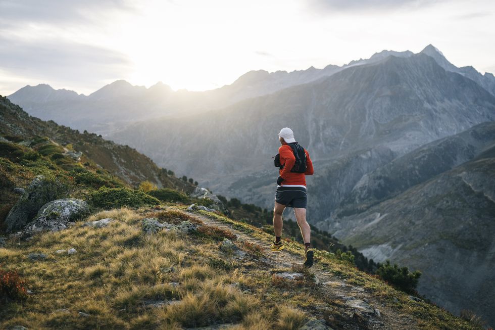 senior male trail runner bounds along mountain trail