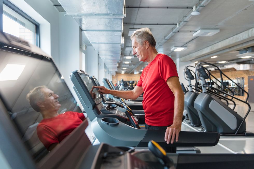 senior man adjusting speed on treadmill at rehab