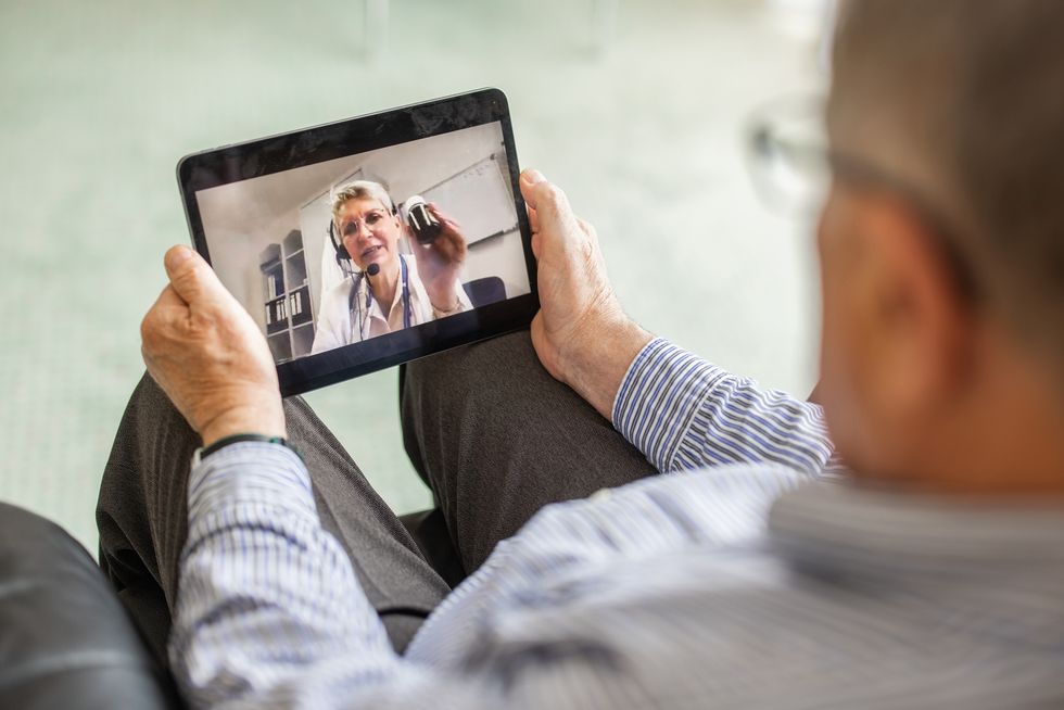 senior man having telemedicine online consultation with female doctor at home on digital tablet