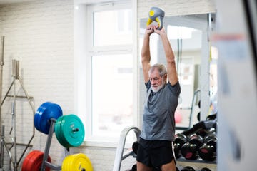 Senior man in gym working out using kettlebells.
