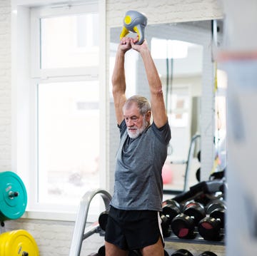 Senior man in gym working out using kettlebells. Senior man in gym working out using kettlebells.