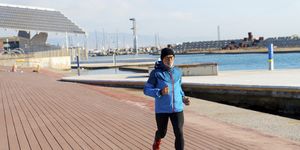 Senior man in sport clothes jogging on harbour dock in a sunny day