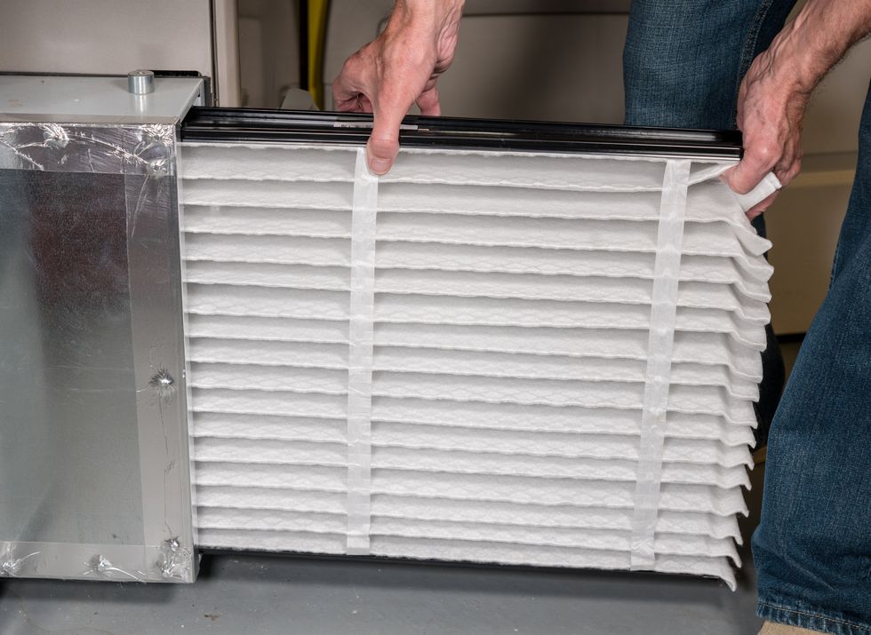winterization of home , winter energy saving tips 2020, senior man inserting a new air filter in a hvac furnace