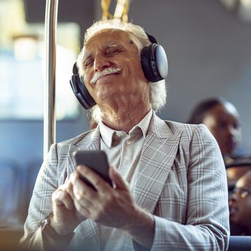 senior man listening to music while riding in a bus