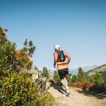 senior man races along a trail in the mountains