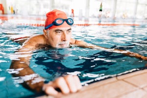 senior man relaxing in water by edge of swimming pool