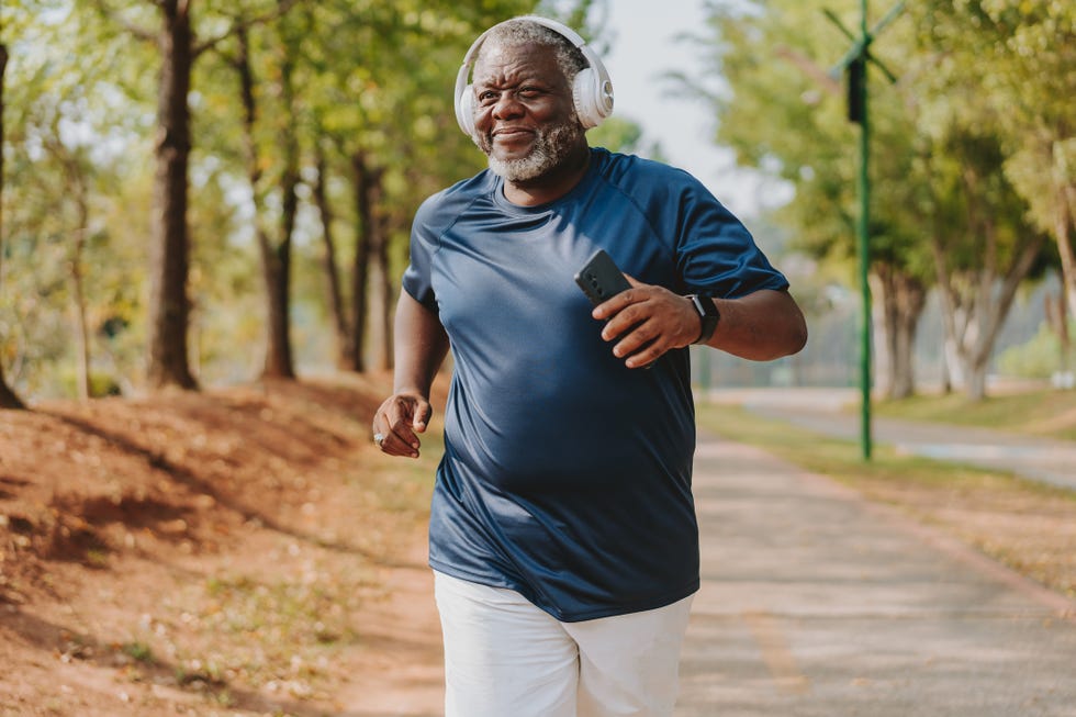 senior man running and listening to music in public park