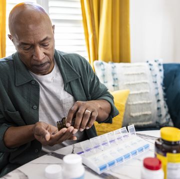 senior man sorting prescription medications at kitchen table