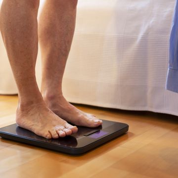 senior man standing on weight scale, low section